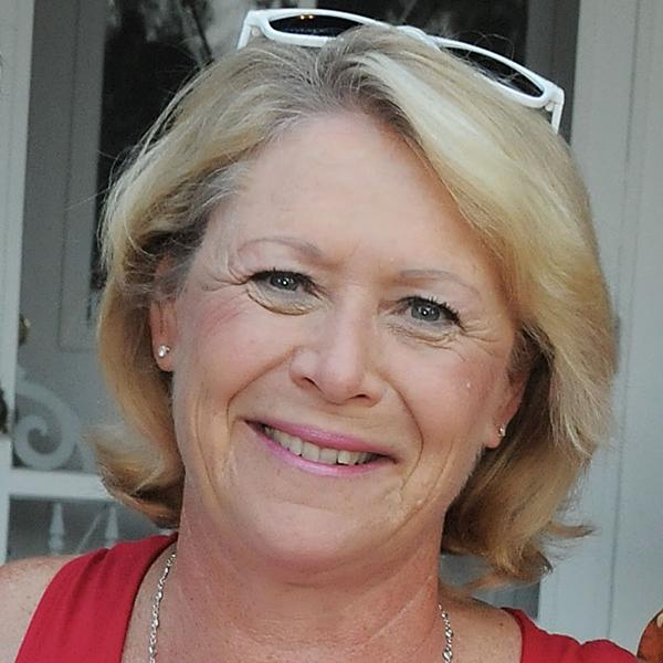 Image of a woman smiling, wearing a bright red top and white sunglasses.